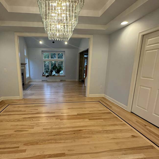 Bright room with floor refinishing by All American Flooring, chandelier, and large window views.