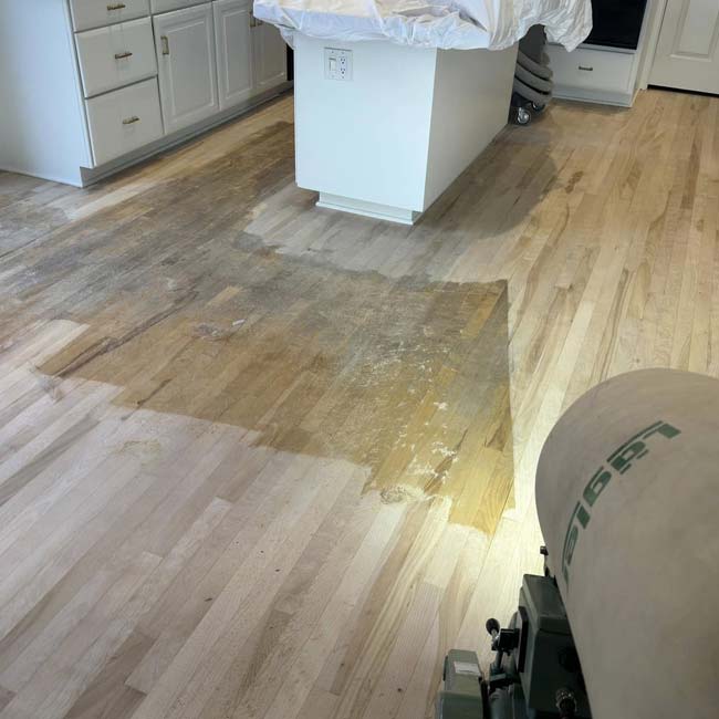 Partially sanded hardwood floor in a kitchen, ready for Hardwood Floor Staining by All American Flooring.
